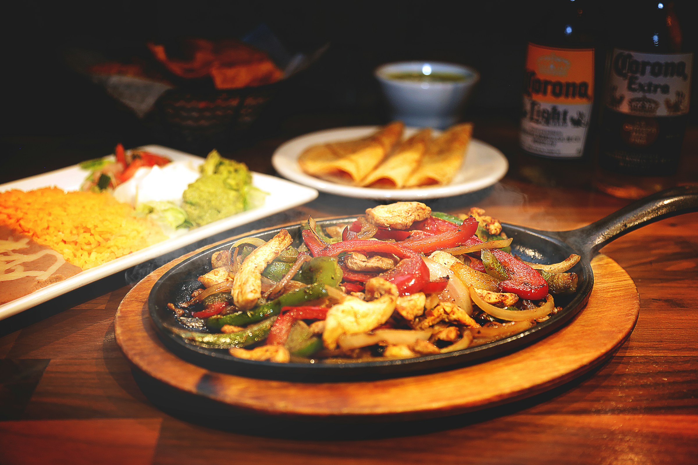 A hot cast-iron fajita skillet with peppers and accompaniments
